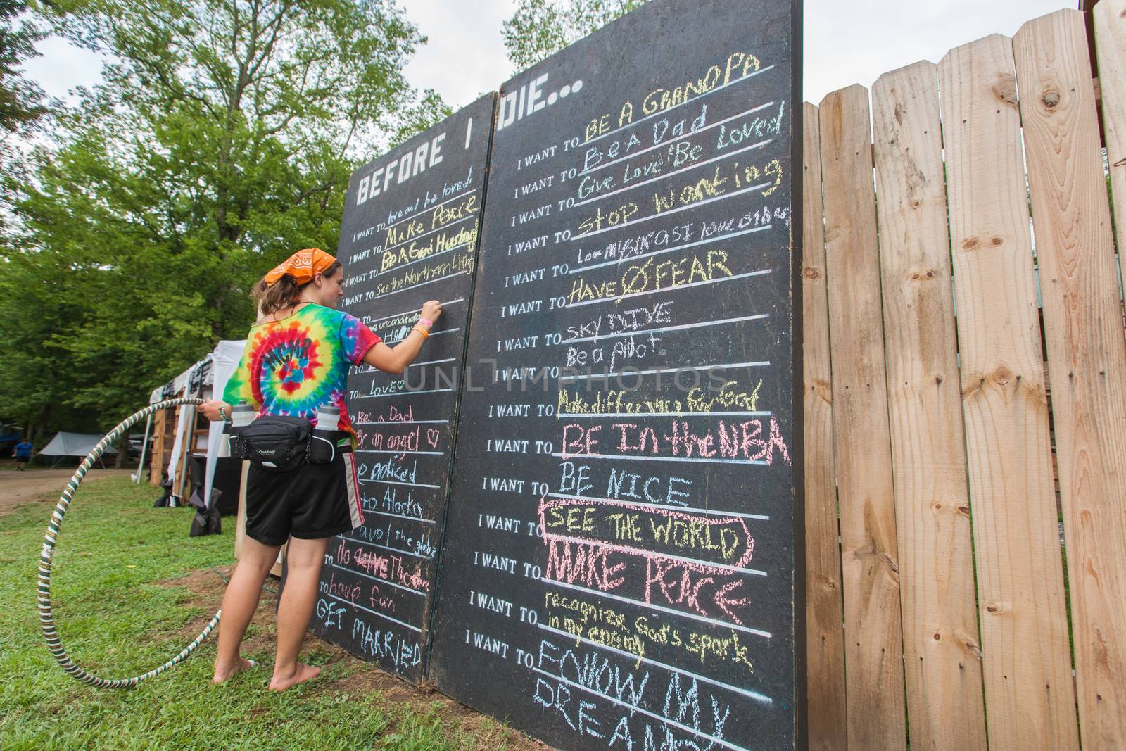 HOT SPRINGS, NC - JULY 7: Single female with hula hoop writing on before I die list blackboard at the Wild Goose Festival on July 7, 2016 in Hot Springs, NC, USA.