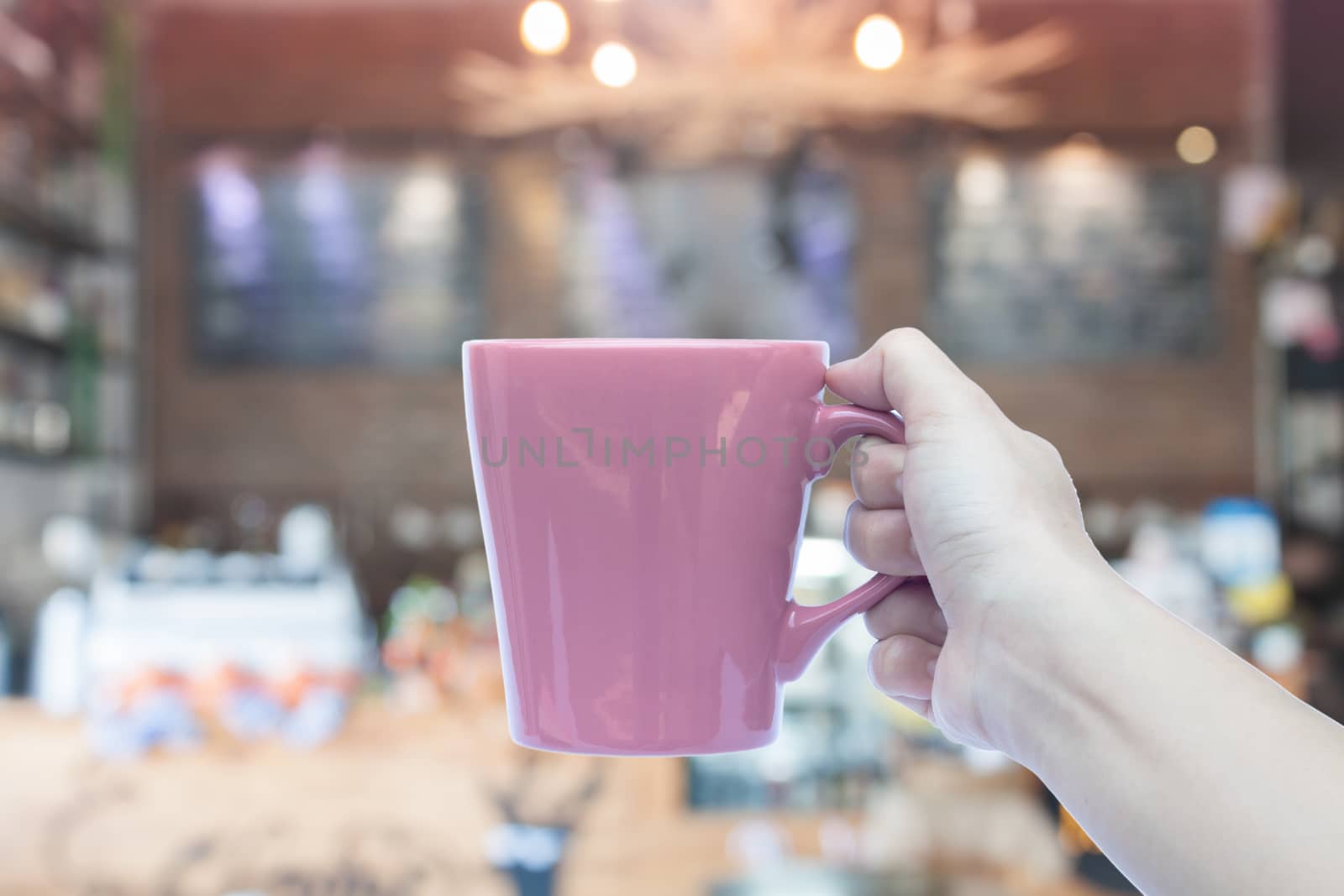 Woman holding coffee mug with blurred cafe background, stock photo