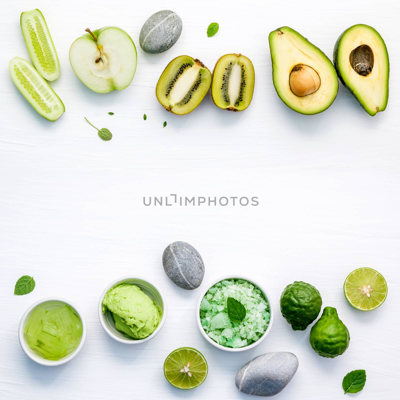 Homemade skin care and body scrubs with green natural ingredients aloe vera ,lime,cucumber ,aromatic salt ,green apple,mint ,rosemary ,kiwi and sage set up on white wooden background with flat lay.