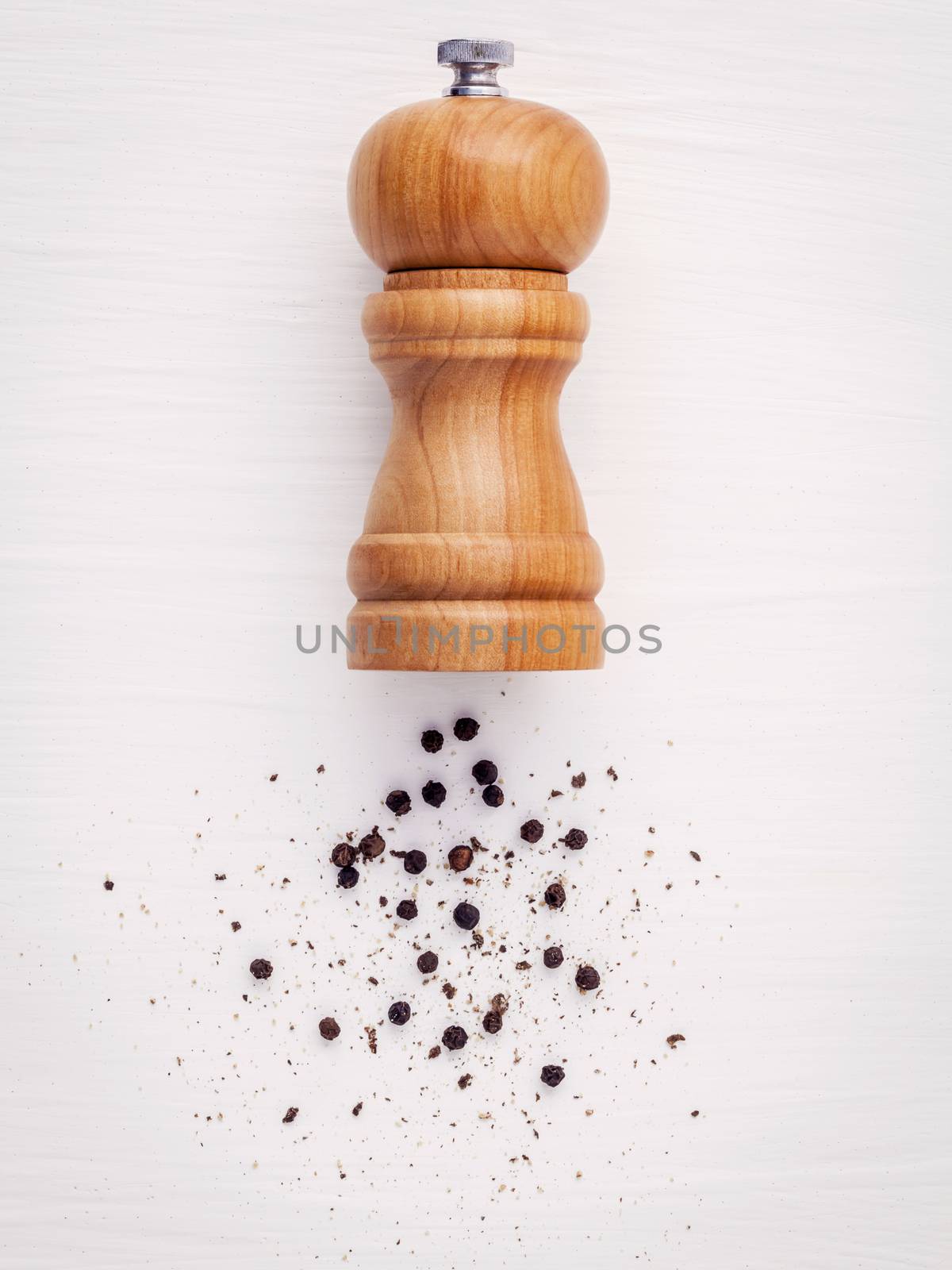 Close up of bottle black pepper mill on white wood table. Seasoning and spices ingredients concept . Flat lay of bottle black pepper mill for culinary seasoning .