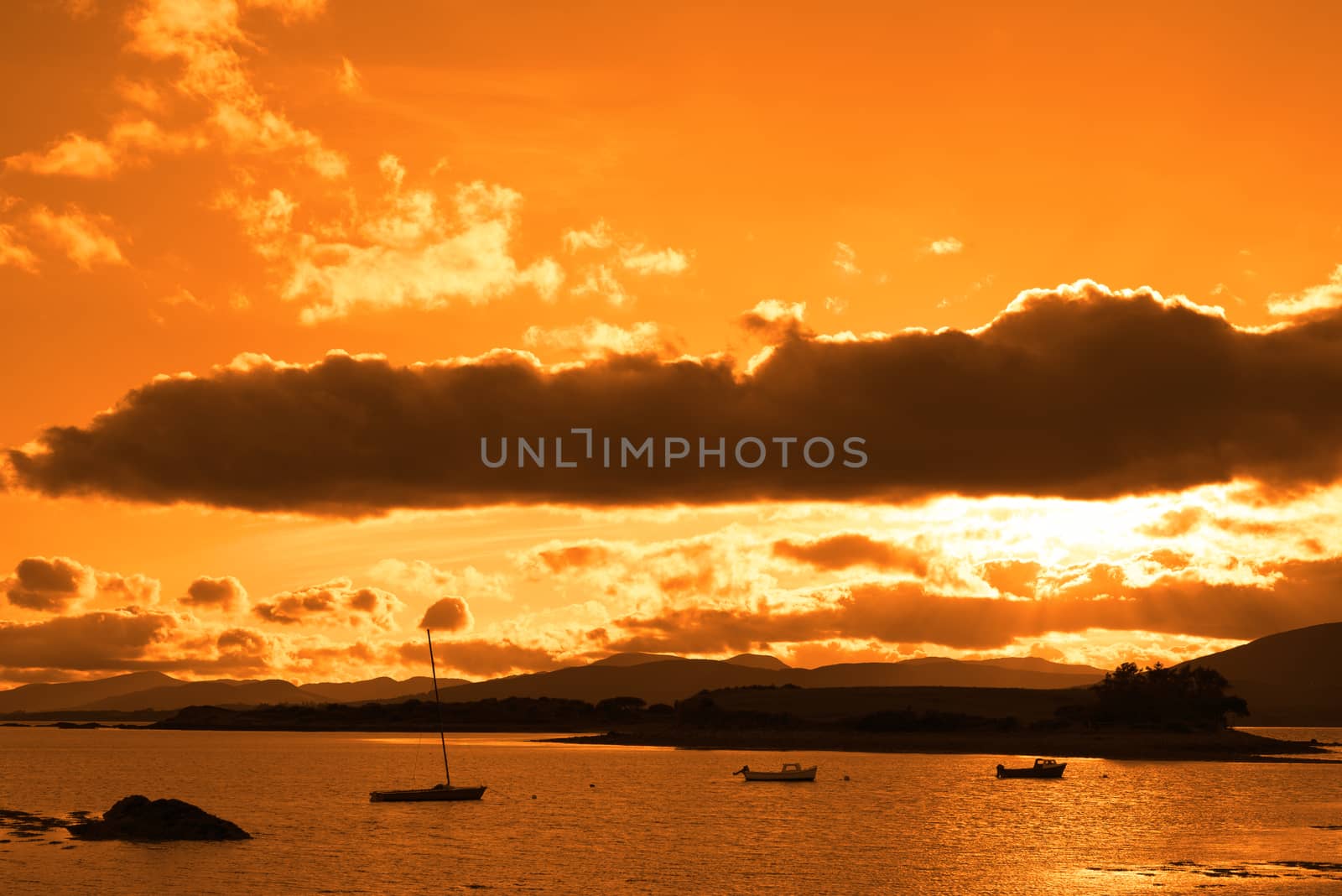 boats in a quiet bay with island near kenmare on the wild atlantic way ireland with an orange sunset
