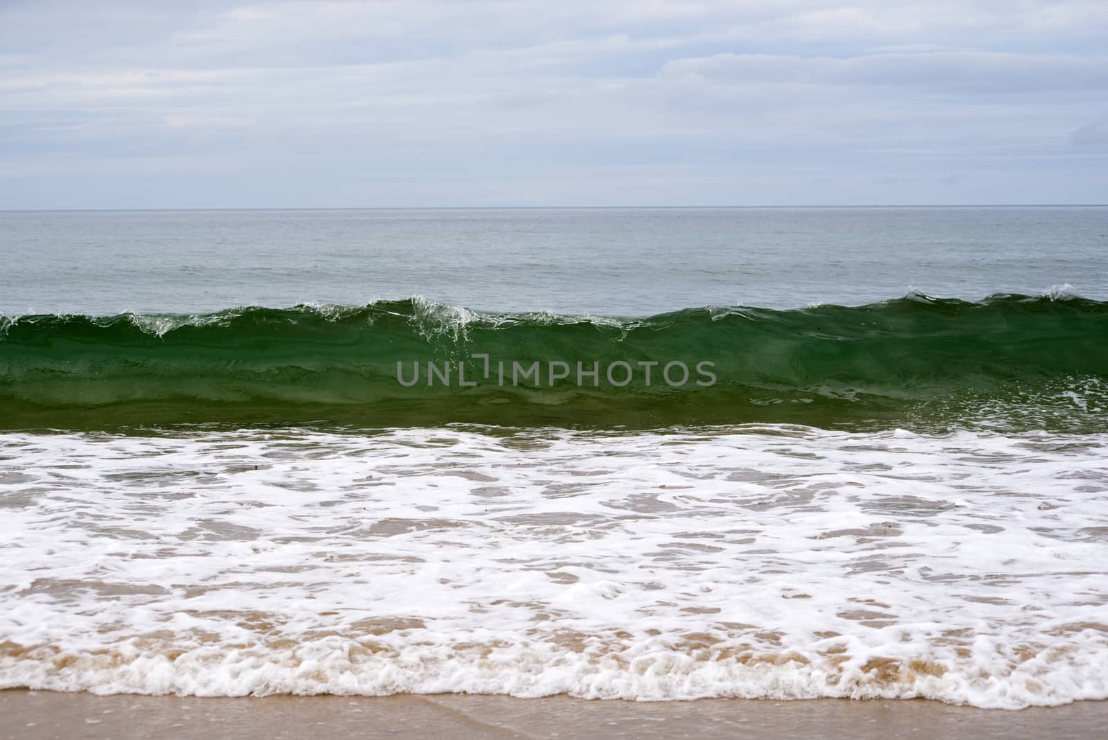 clean green waves breaking on the beach by morrbyte