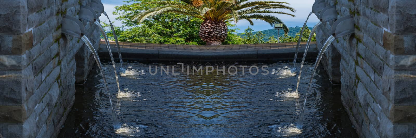 Modern fountain with six spotlighted water in the background sea and countryside.