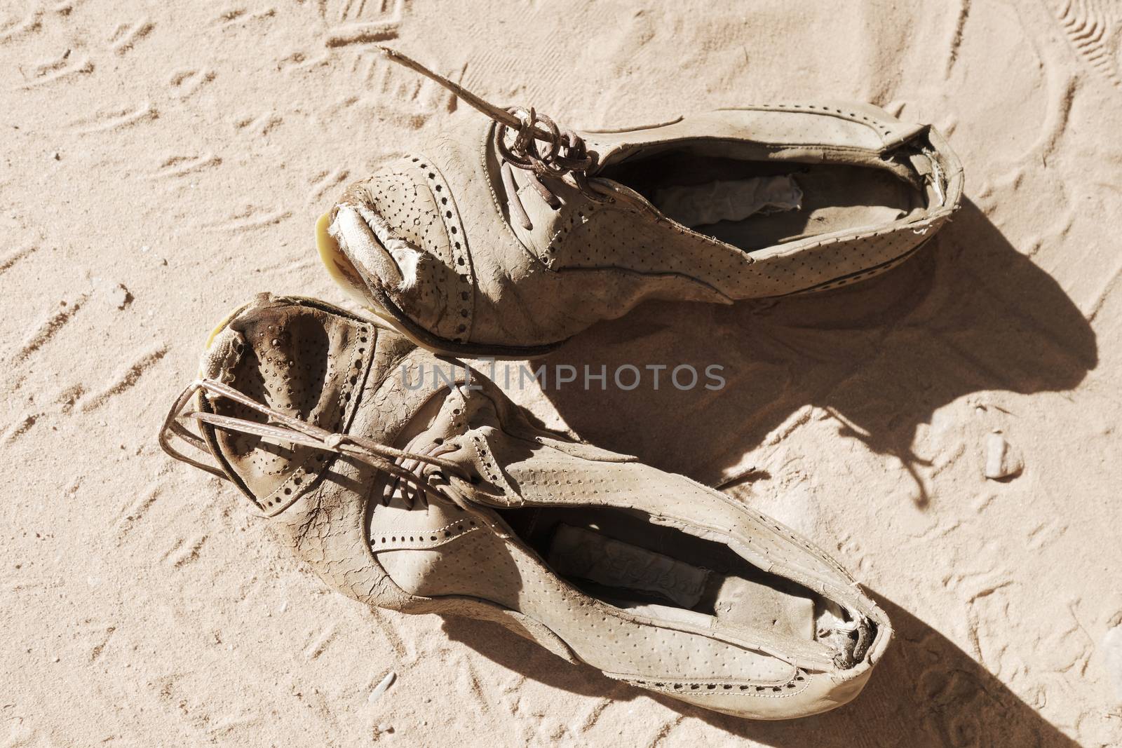 old dirty pair of shoes on sand background                               