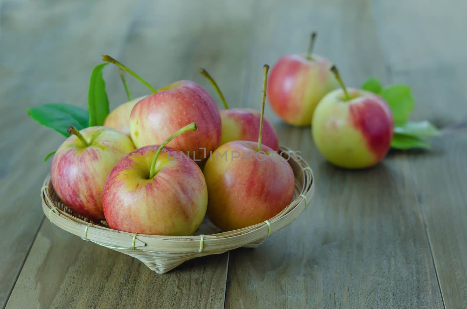 Red and yellow apple  with bamboo basket , organic fresh fruit on wooden background