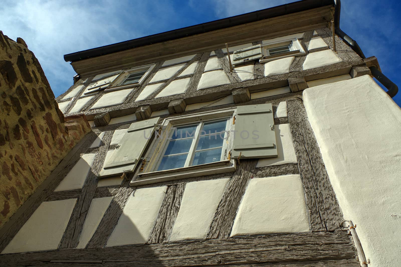 Part of a residential tudor style house with blue sky in background by evolutionnow