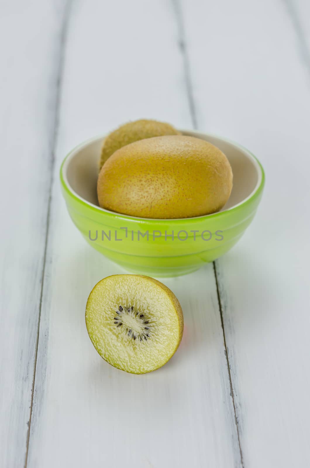 Kiwi fruit in a bowl on wooden background