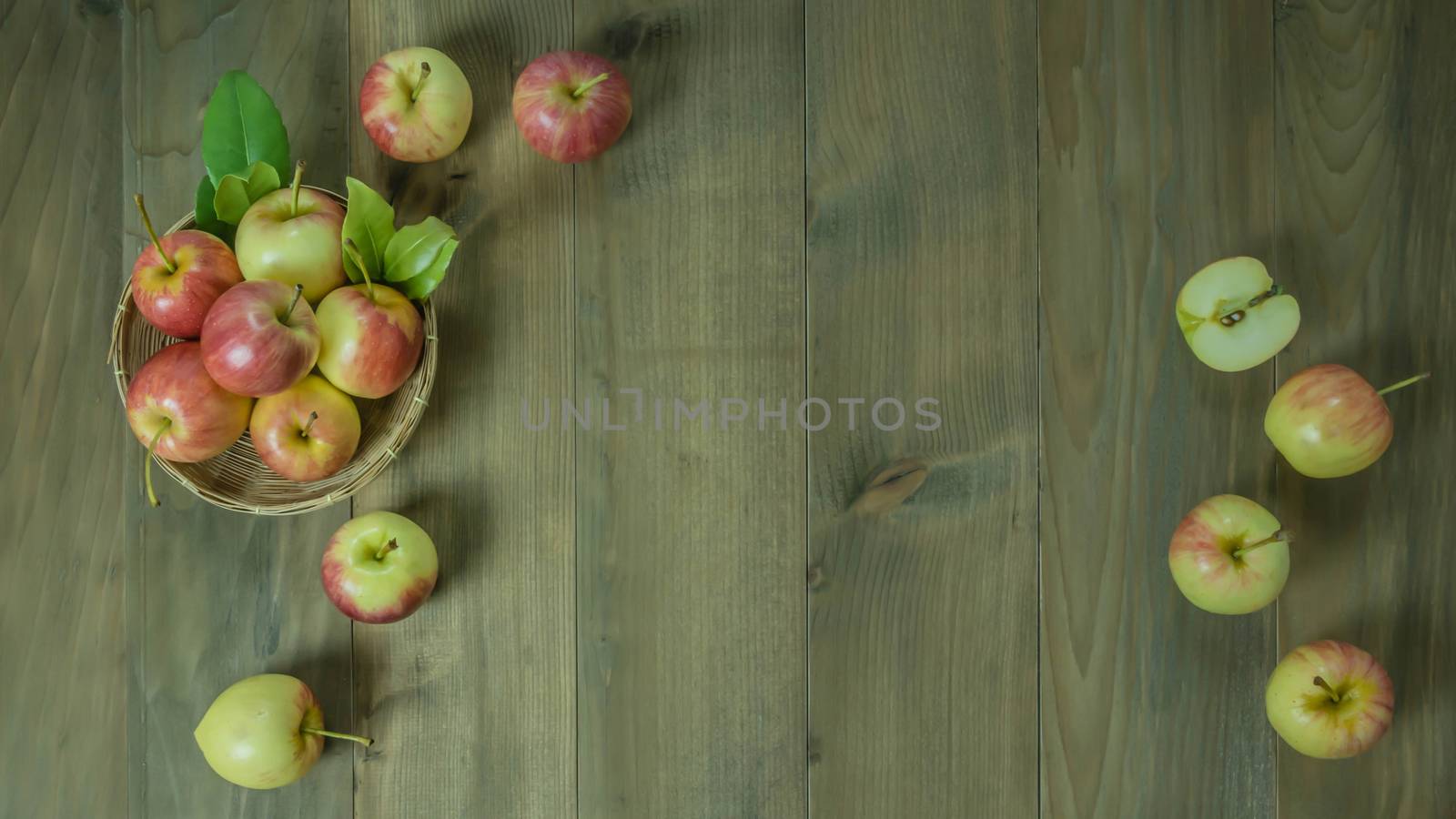 Top view red and yellow apple with leaves and  bamboo basket on wooden background with free space for text