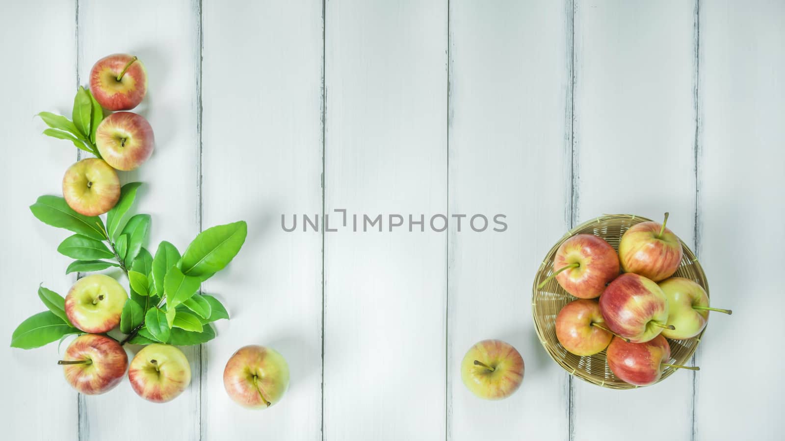 Top view red and yellow apple with leaves and  bamboo basket on  white wooden background with free space for text