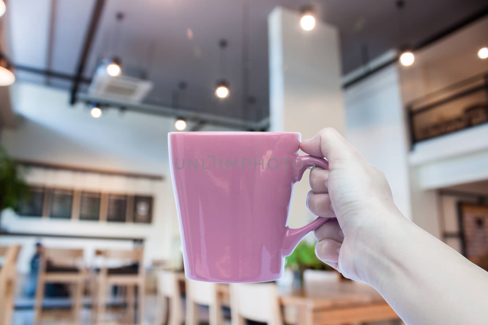 Woman holding coffee cup with abstract blur coffee shop, stock photo