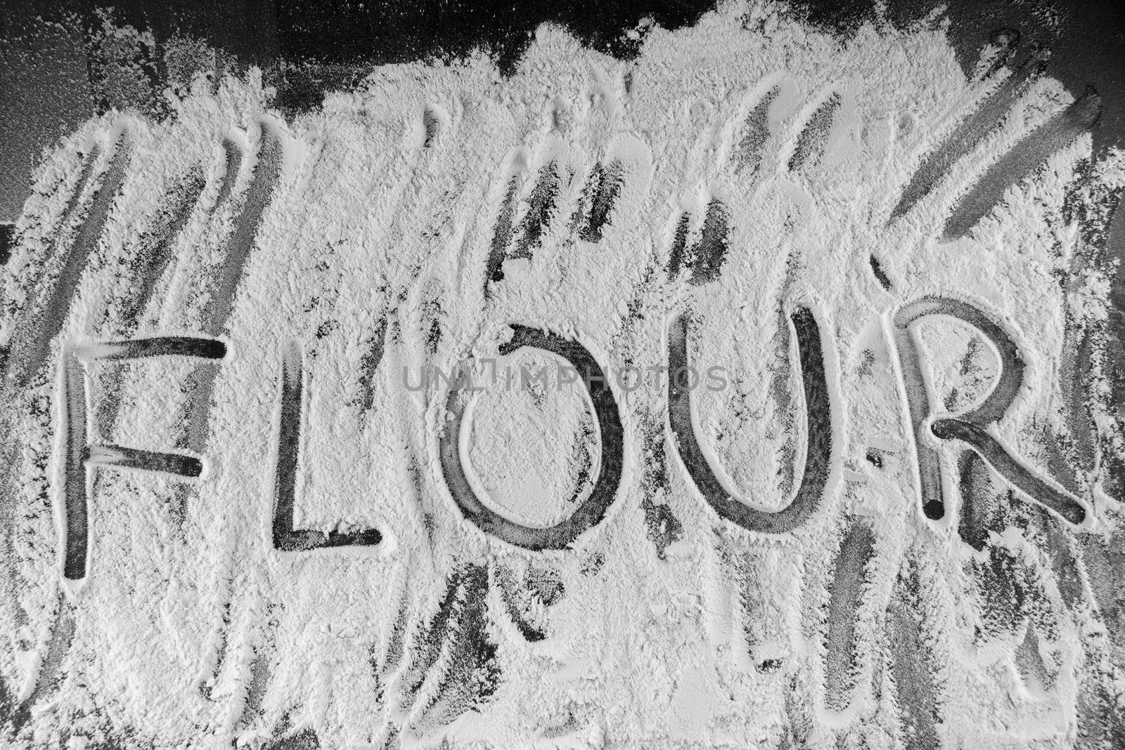 Word flour written in flour on table.