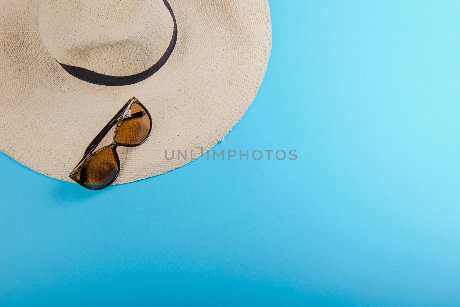 Straw hat and sunglasses on blue background. beach equipment.