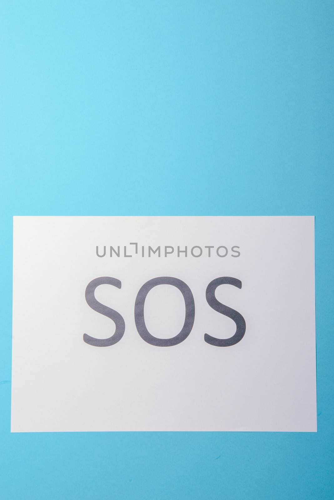 Word SOS written on white paper. Blue background
