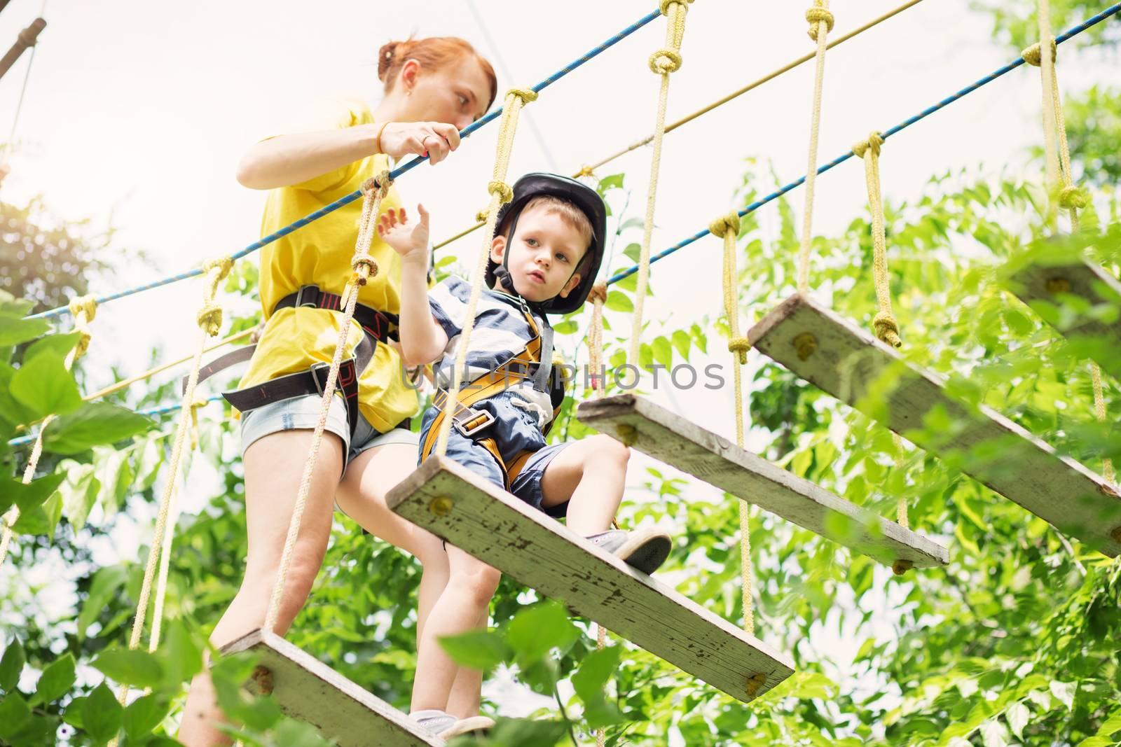 Kids climbing in adventure park. Boy enjoys climbing in the rope by natazhekova