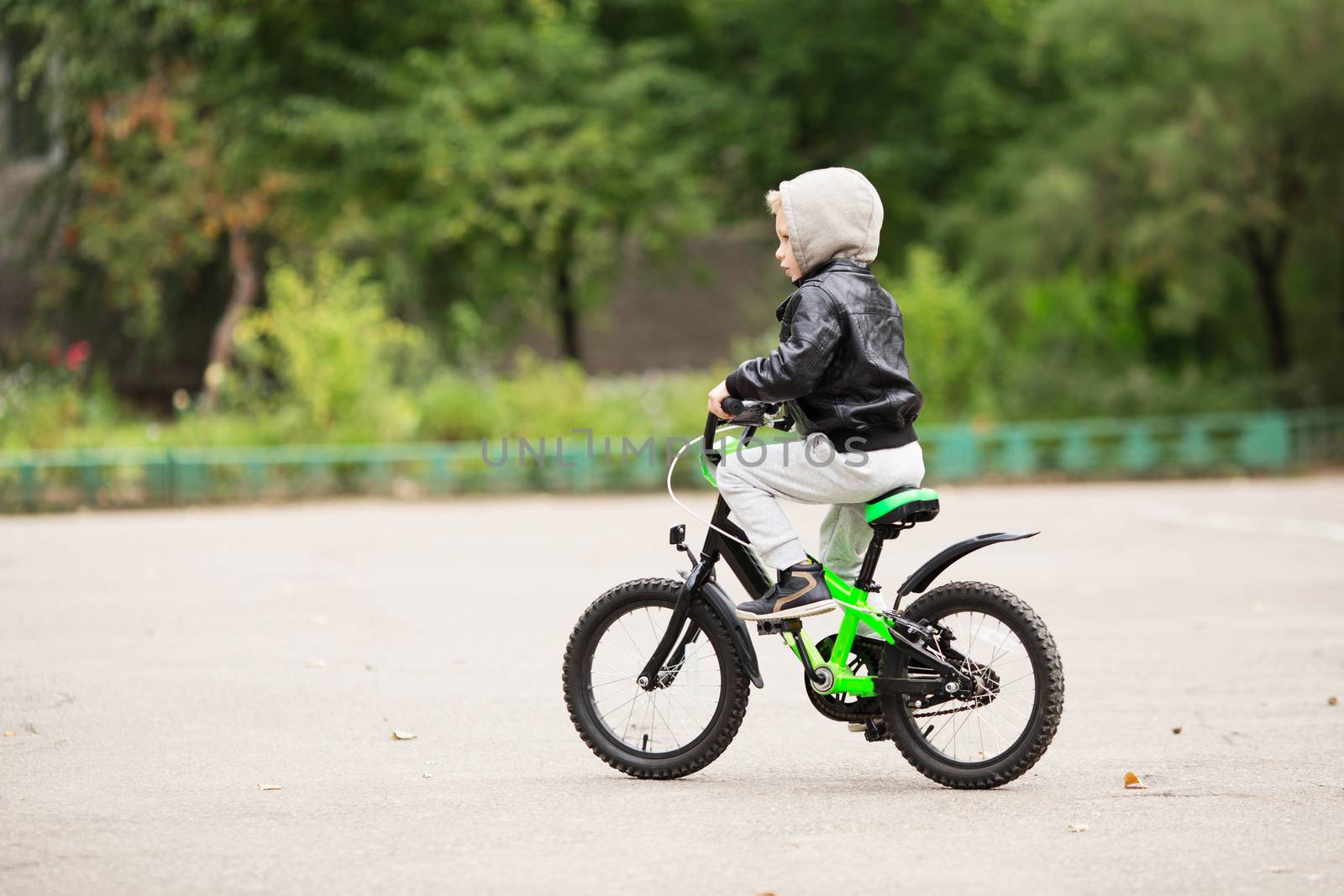 portrait of adorable little urban boy wearing black leather jacket. City style. Urban kids. The boy learns to ride a bike. Child driving a bicycle.