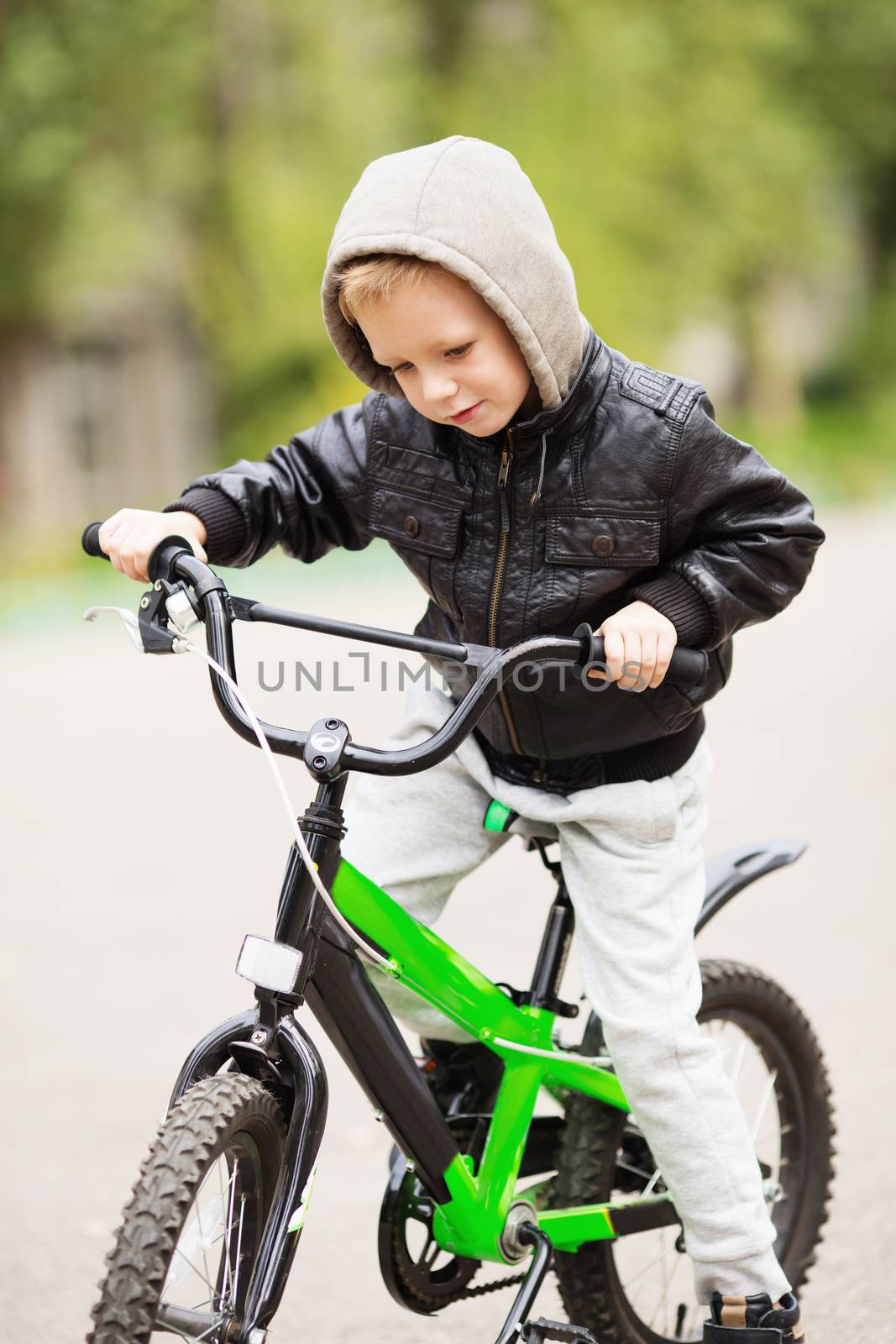 portrait of adorable little urban boy wearing black leather jacket. City style. Urban kids. The boy learns to ride a bike. Child driving a bicycle.