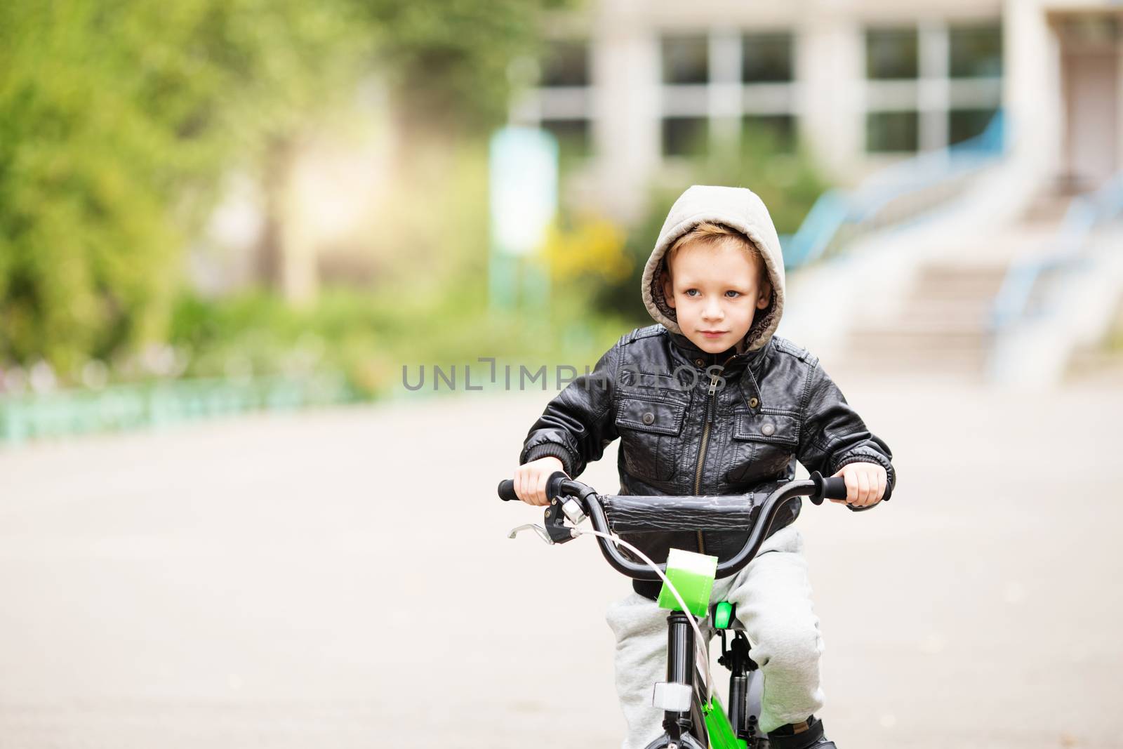 portrait of adorable little urban boy wearing black leather jacket. City style. Urban kids. The boy learns to ride a bike. Child driving a bicycle.