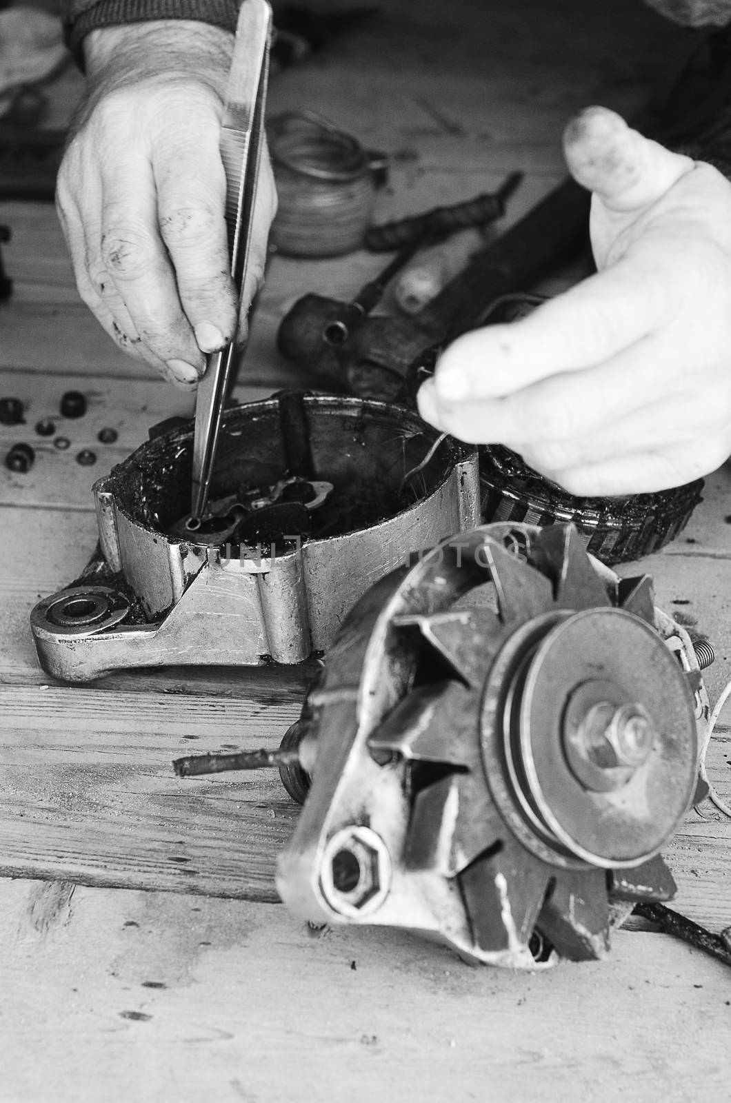 Man's hand at work with the tools and gear. Black & white, vertical