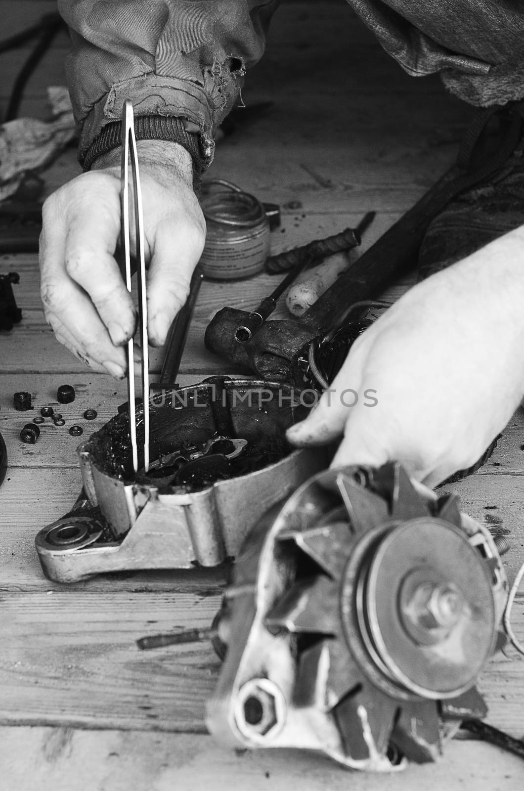 Man's hand at work with the tools, tongs and gear. Black & white, vertical