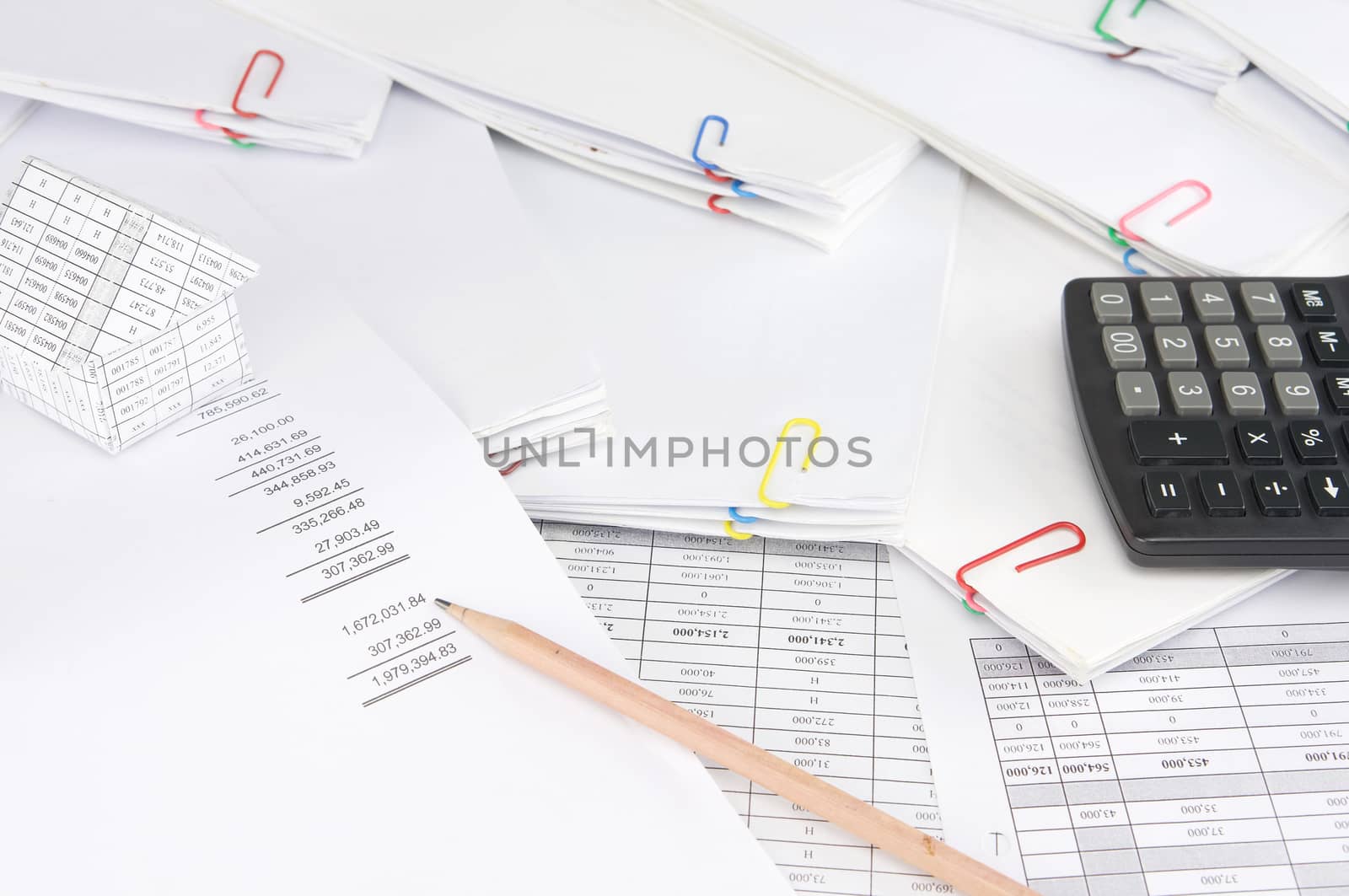 Pencil on earnings statement have blur house and calculator on stack paperwork of report and receipt with colorful paperclip as background.