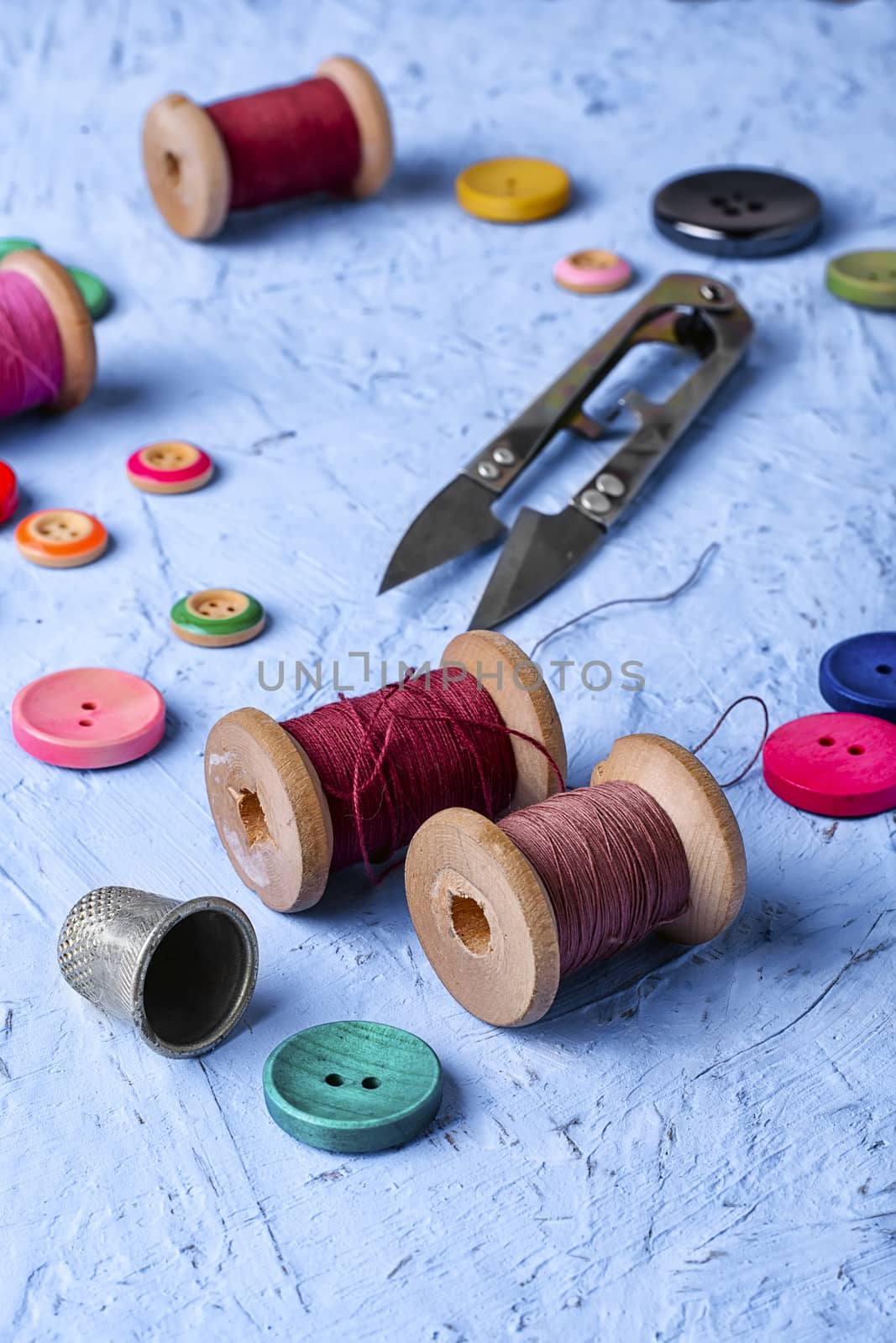 Set of buttons and thread on bright blue background