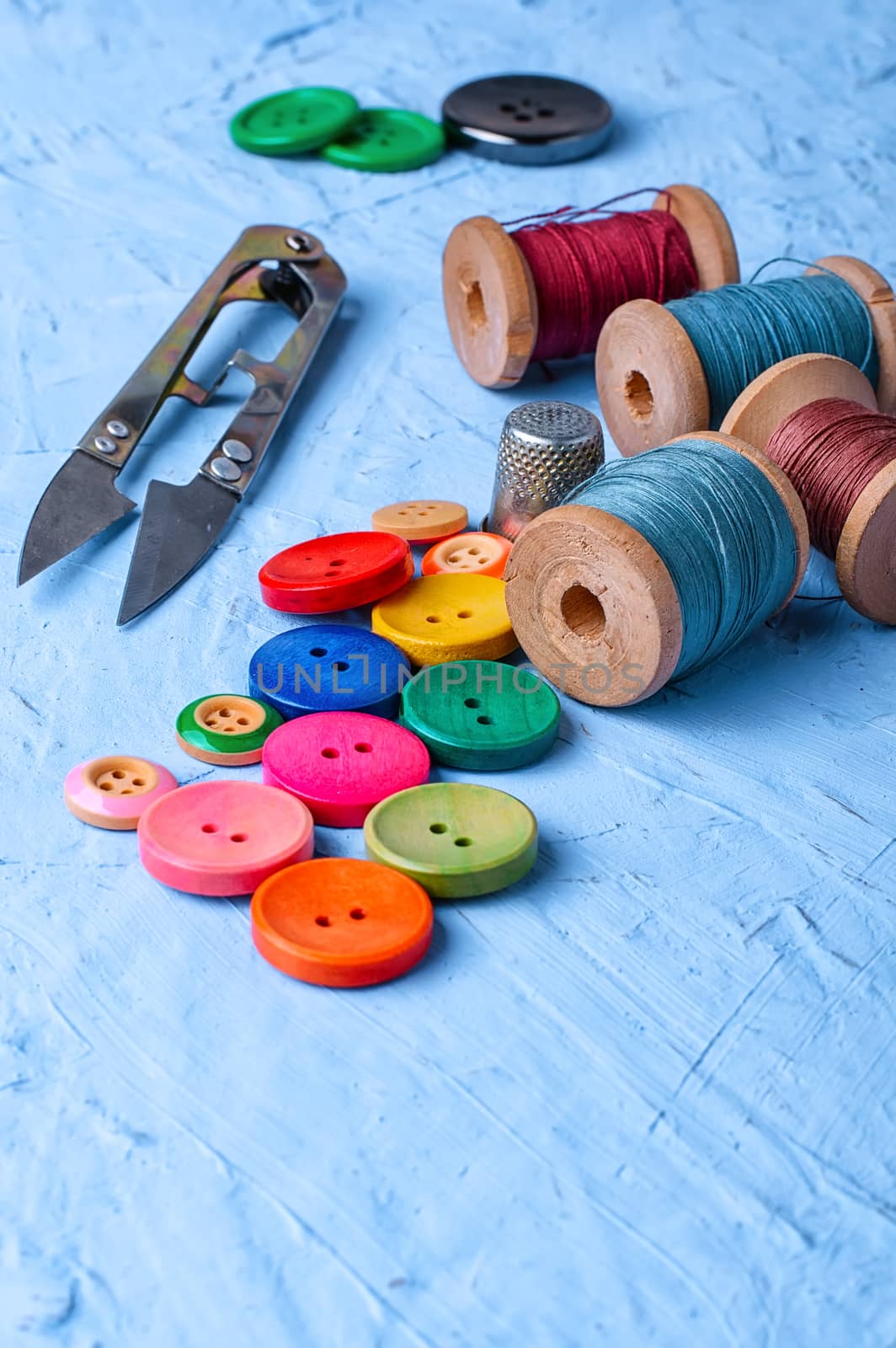 Set of buttons and thread on bright blue background