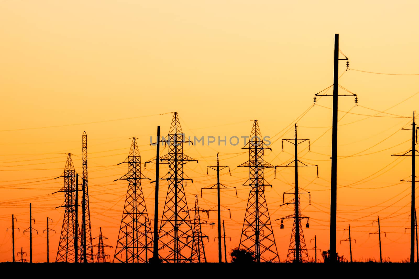 Power lines pylons at bright red orange sunset