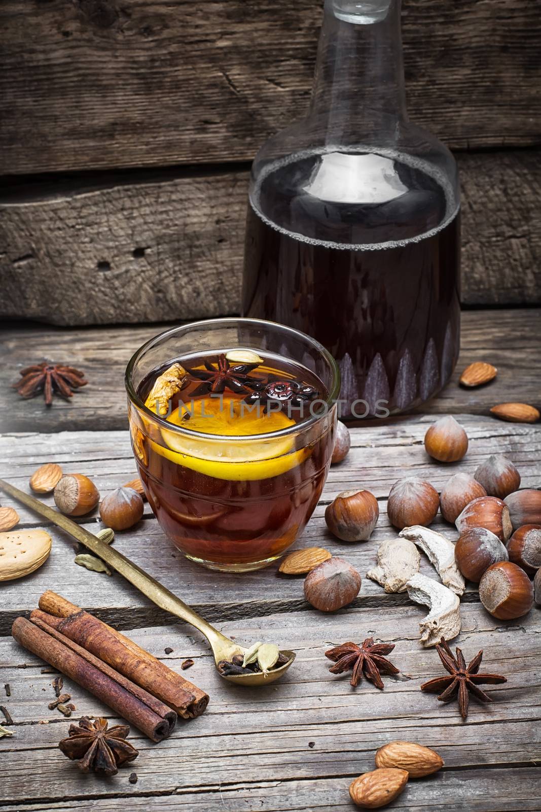 glass of mulled wine with almonds,cinnamon and anise on background of carafe of wine