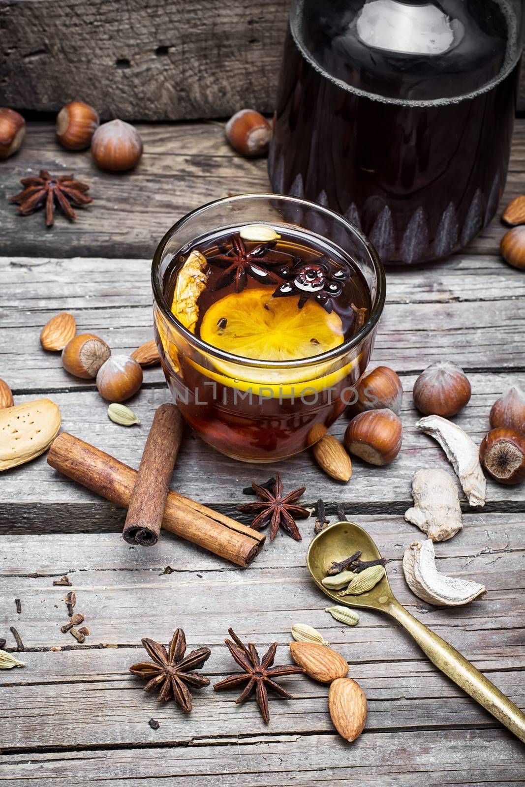 glass of mulled wine with almonds,cinnamon and anise on background of carafe of wine