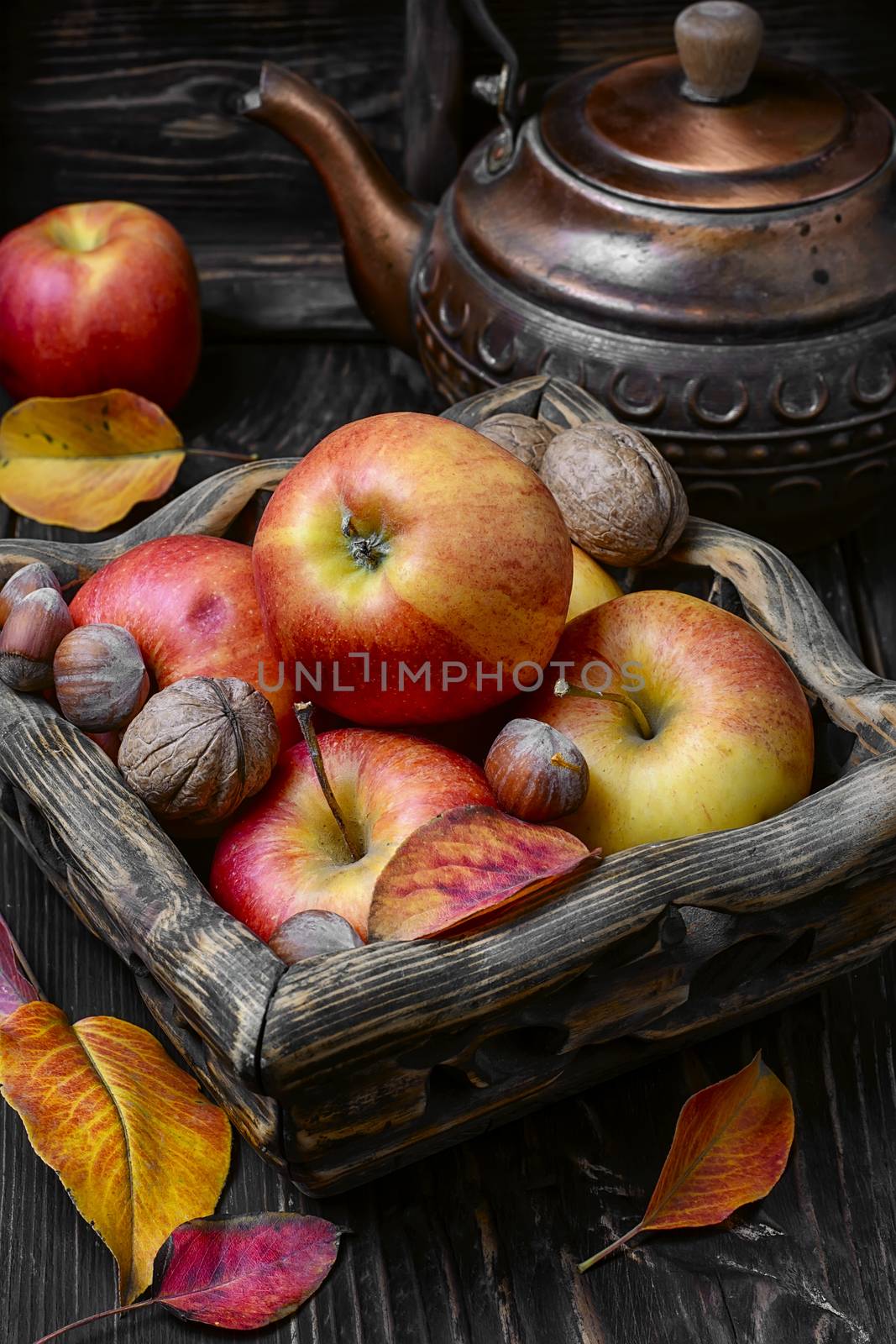 Harvest of red apples and nuts on dark wooden background