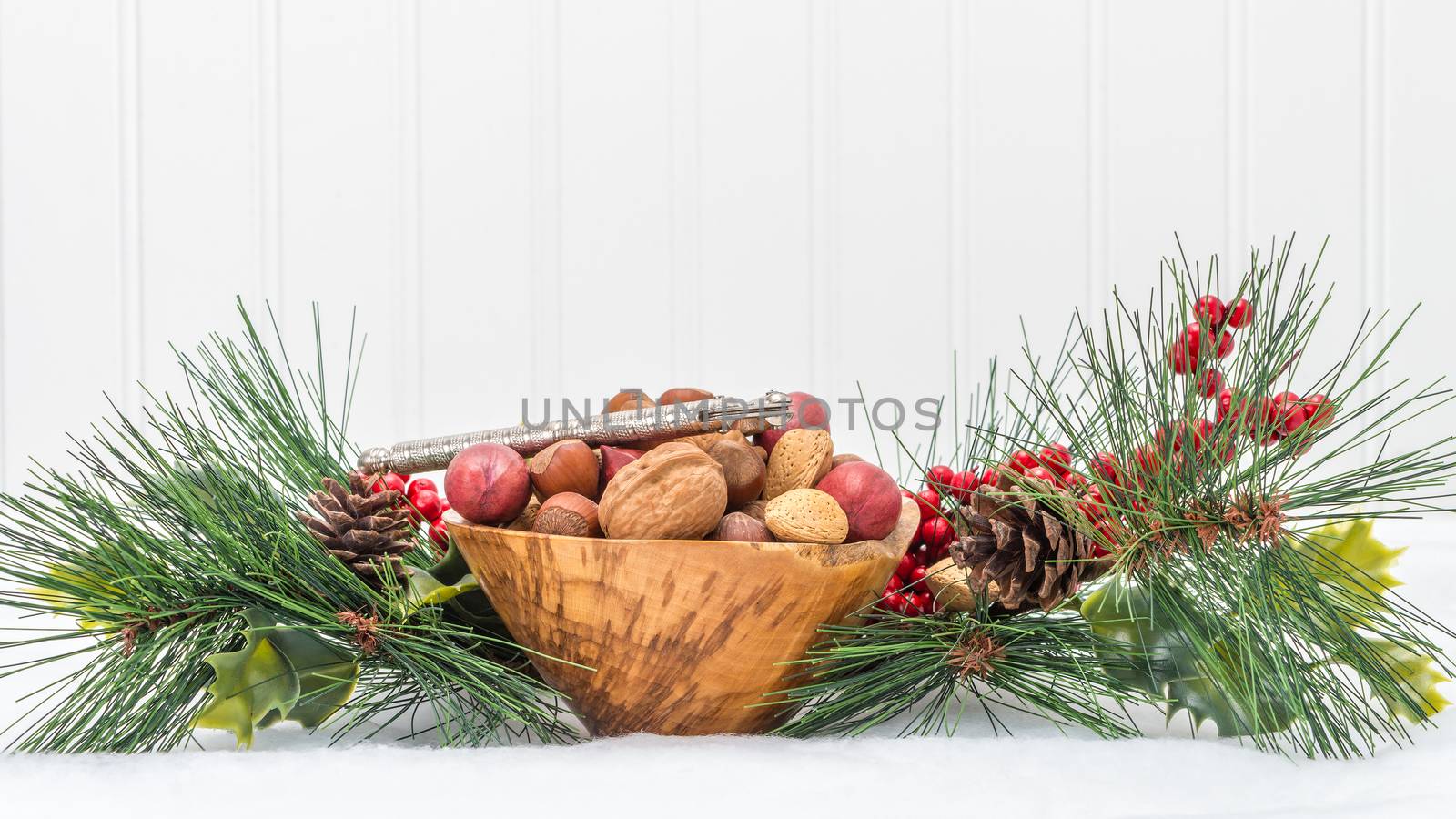 Wooden bowl filled with mixed nuts surrounded by a seasonal garland.