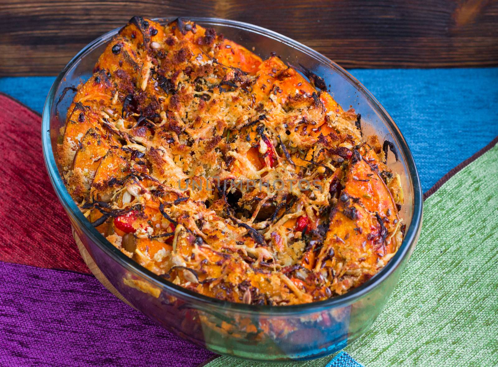 Vegetarian dish of orange pumkin, mixed vegetables, herbs and cheese baked in oven