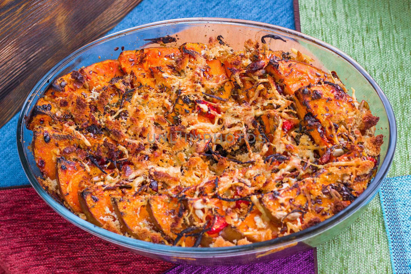 Vegetarian dish of orange pumkin, mixed vegetables, herbs and cheese baked in oven