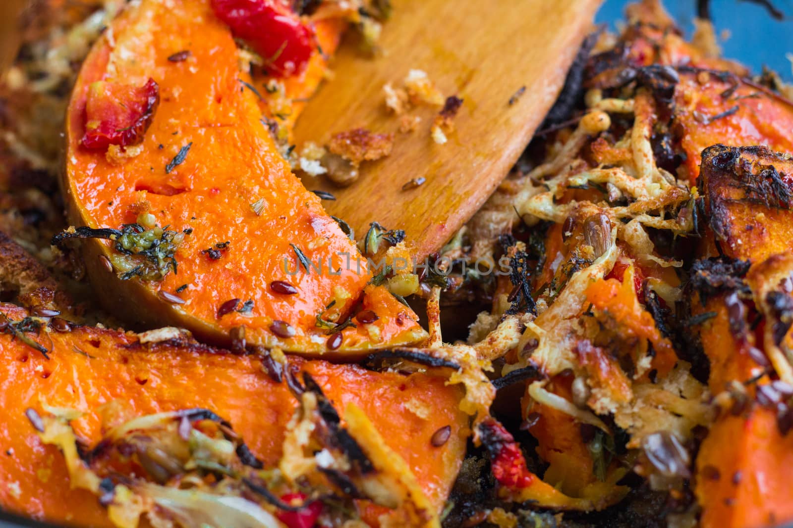 Vegetarian baked dish close-up with orange pumkin, mixed vegetables, herbs, cheese