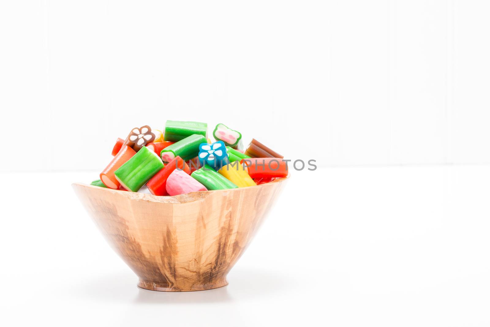 Colorful soft chewy candy in a wooden bowl with ample copy space.
