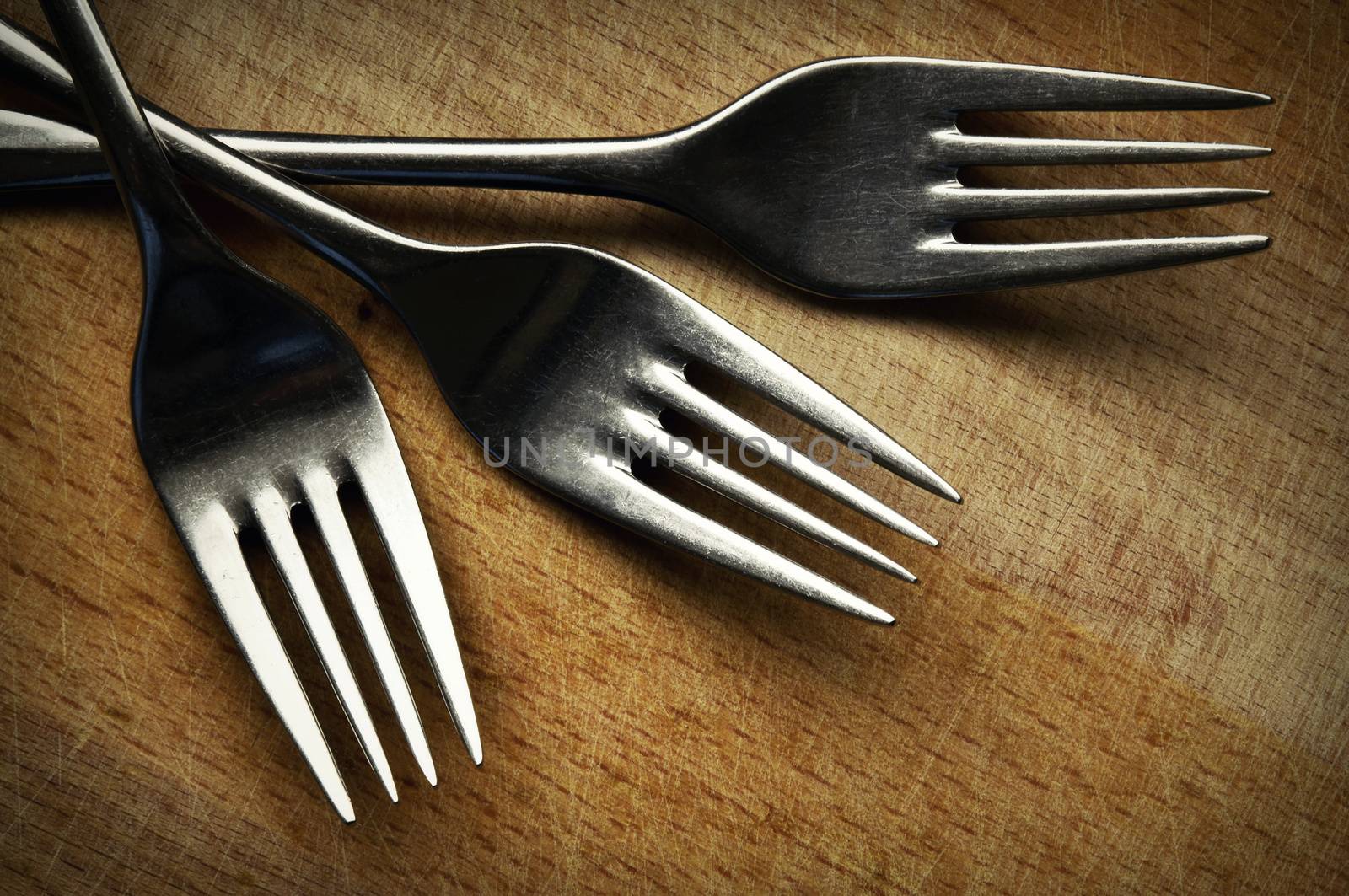 retro background Three stainless steel fork on the kitchen board