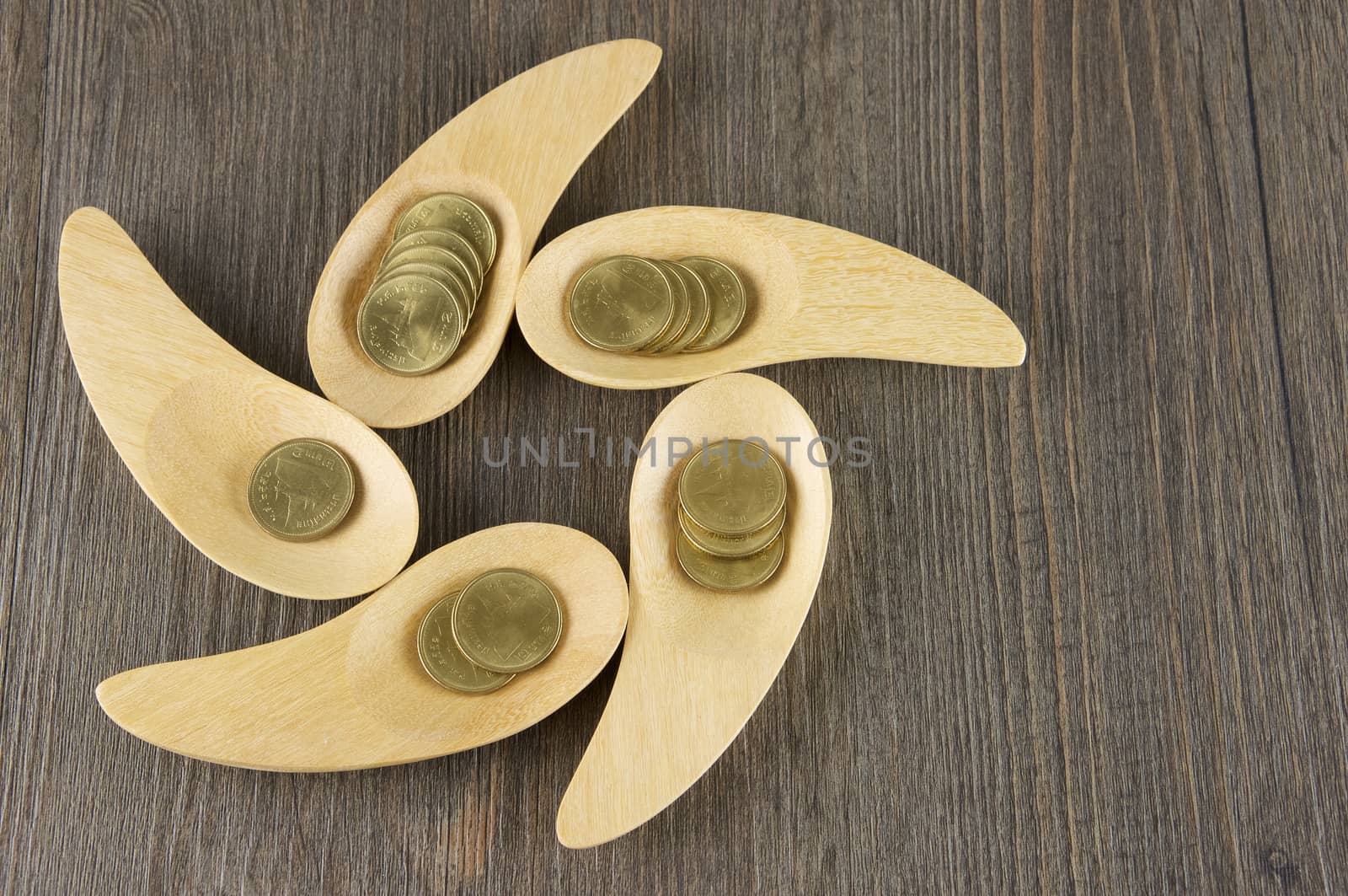 Gold coins in wooden spoon place as rowel on wood background.