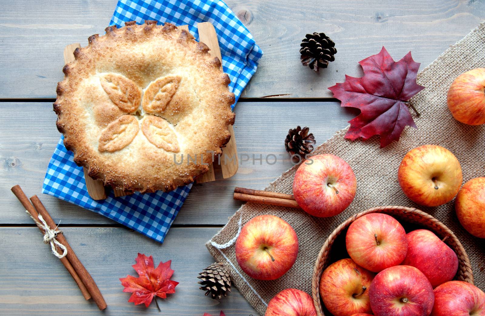 Apple pie with ingredients, cinammon sticks and autumn leaves 