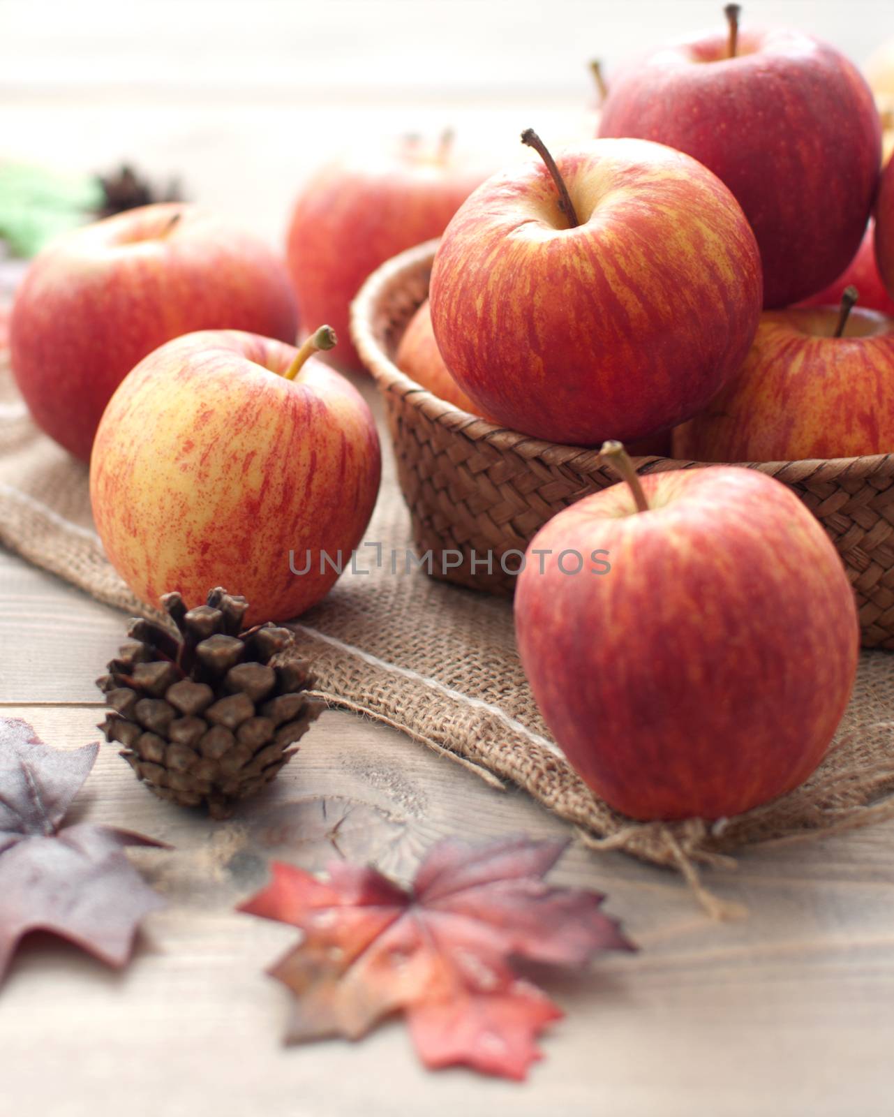 Autumn leaves with apples over a wooden background