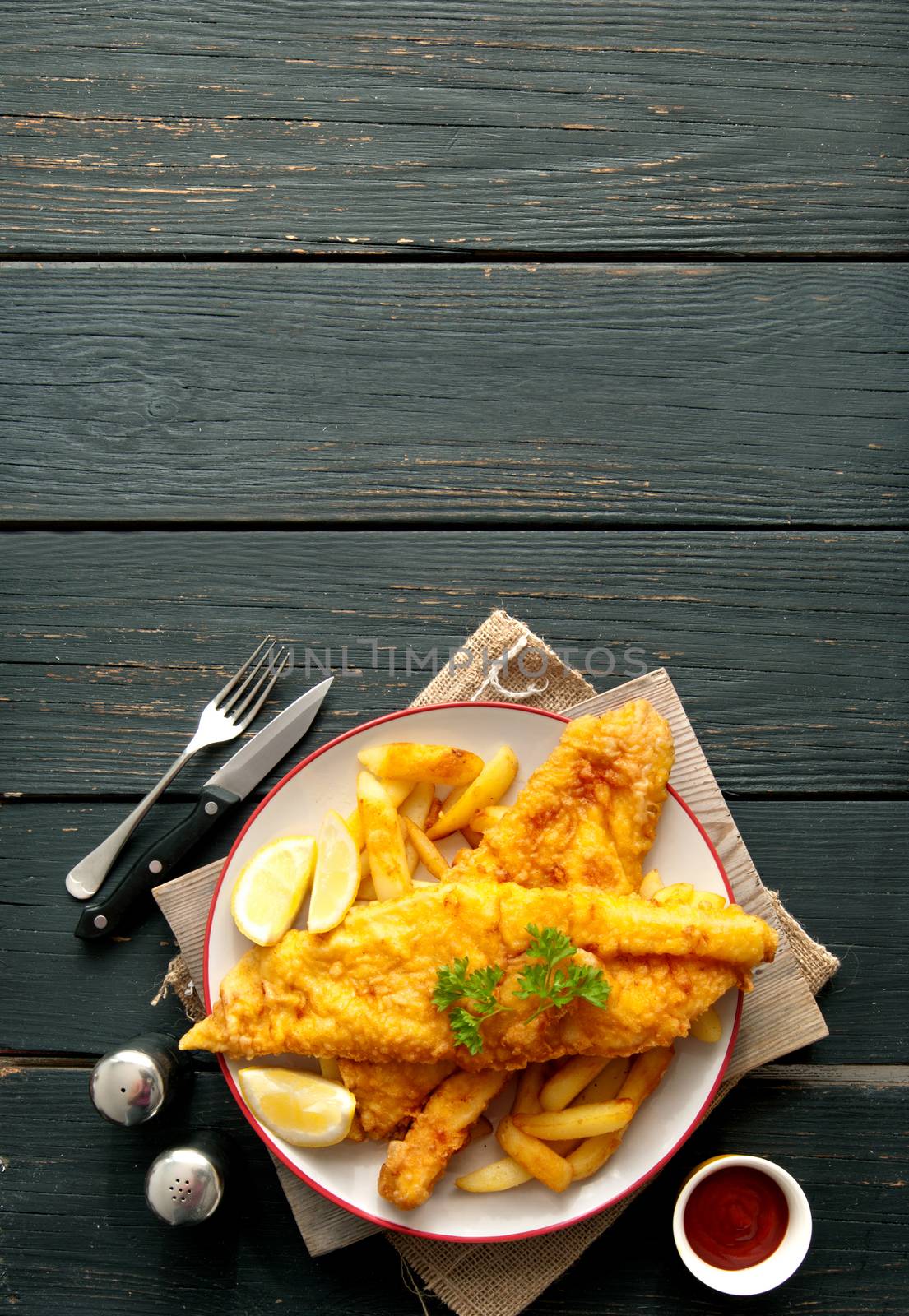 Two pieces of battered fish on a plate with chips 