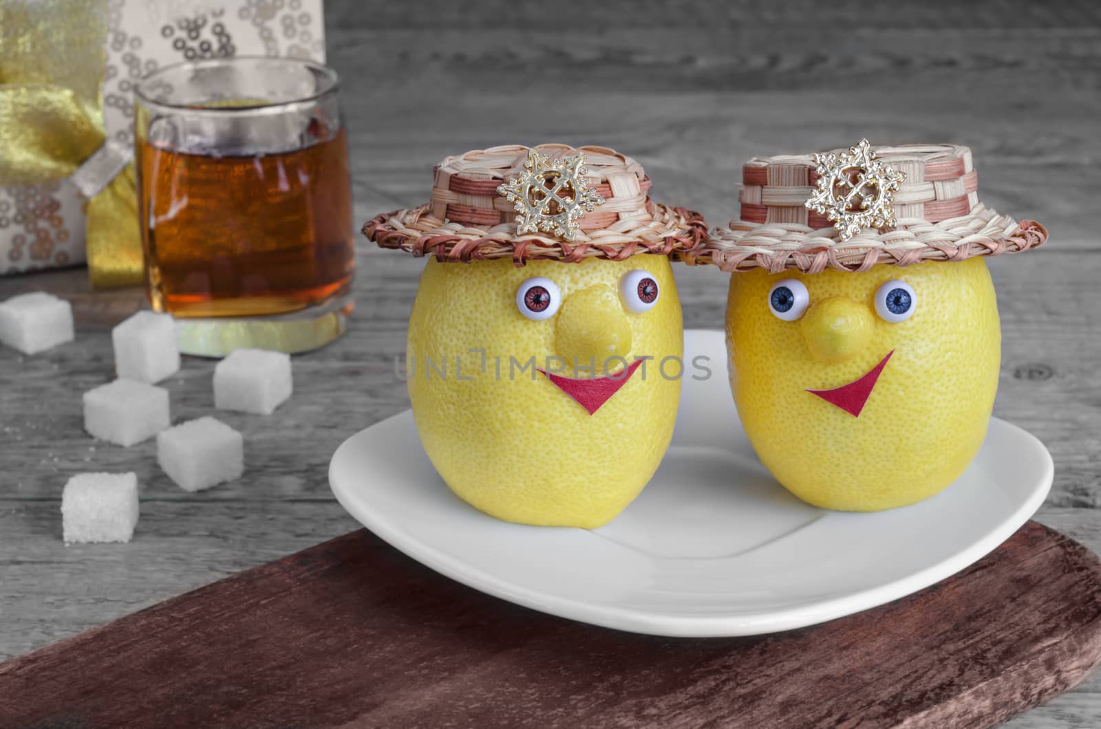 Lemons with sugar on a white plate and brown Board. Tea and gray wooden background.