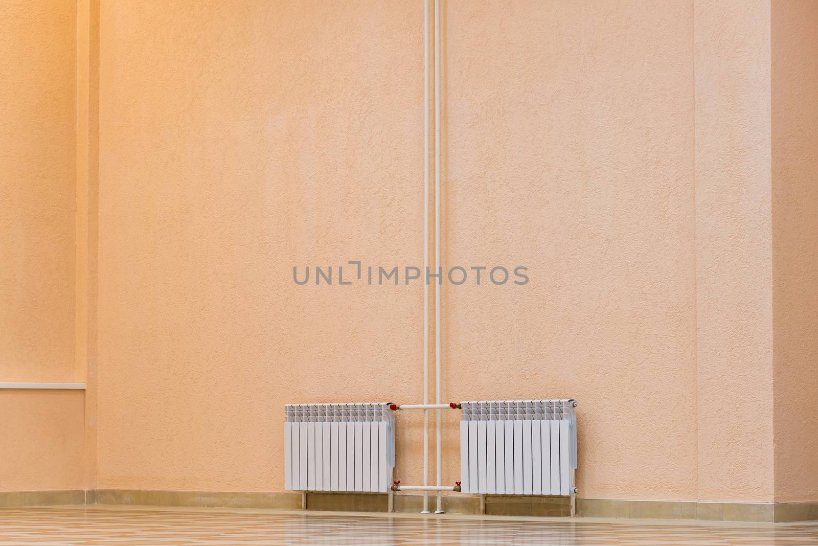 White new radiator on pink wall in building by olgavolodina