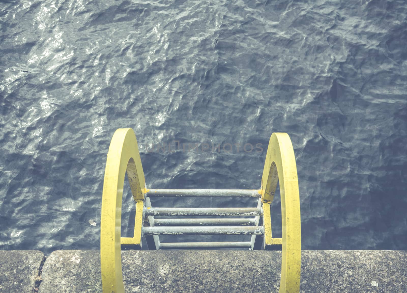 Conceptual Image Of A Yellow Ladder Into Blue Ocean Water At A Harbor