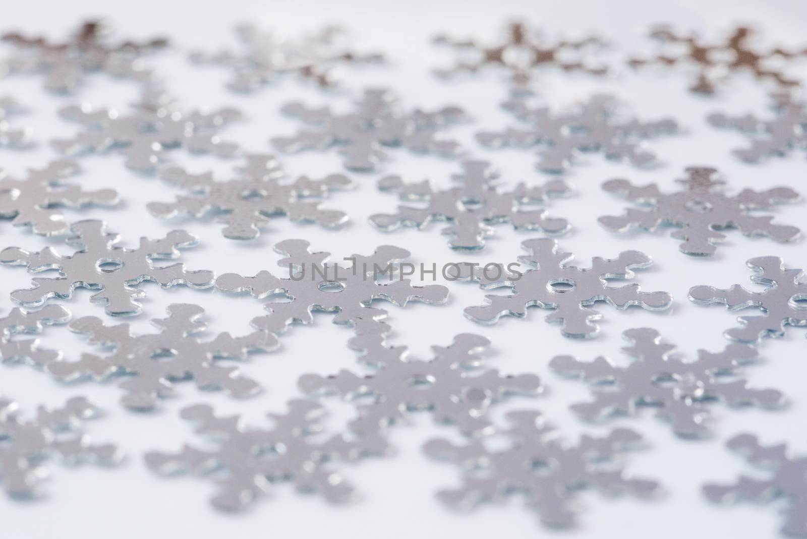 Christmas decoration of silver confetti snow flake against white background with nice boke. Close up confetti with shallow DOF