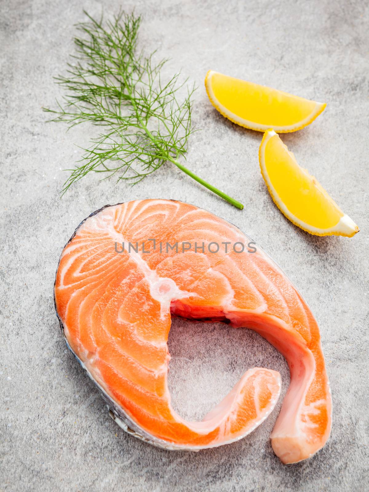 Fresh salmon fillet slice on dark stone background with  fennel and lemon propose  for cooking . Healthy food concept.