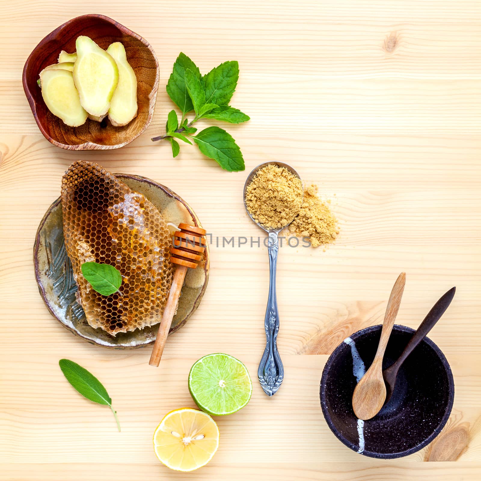 Honeycomb in wooden bowl with herbs mint ,thyme and sage set up on white wooden background.