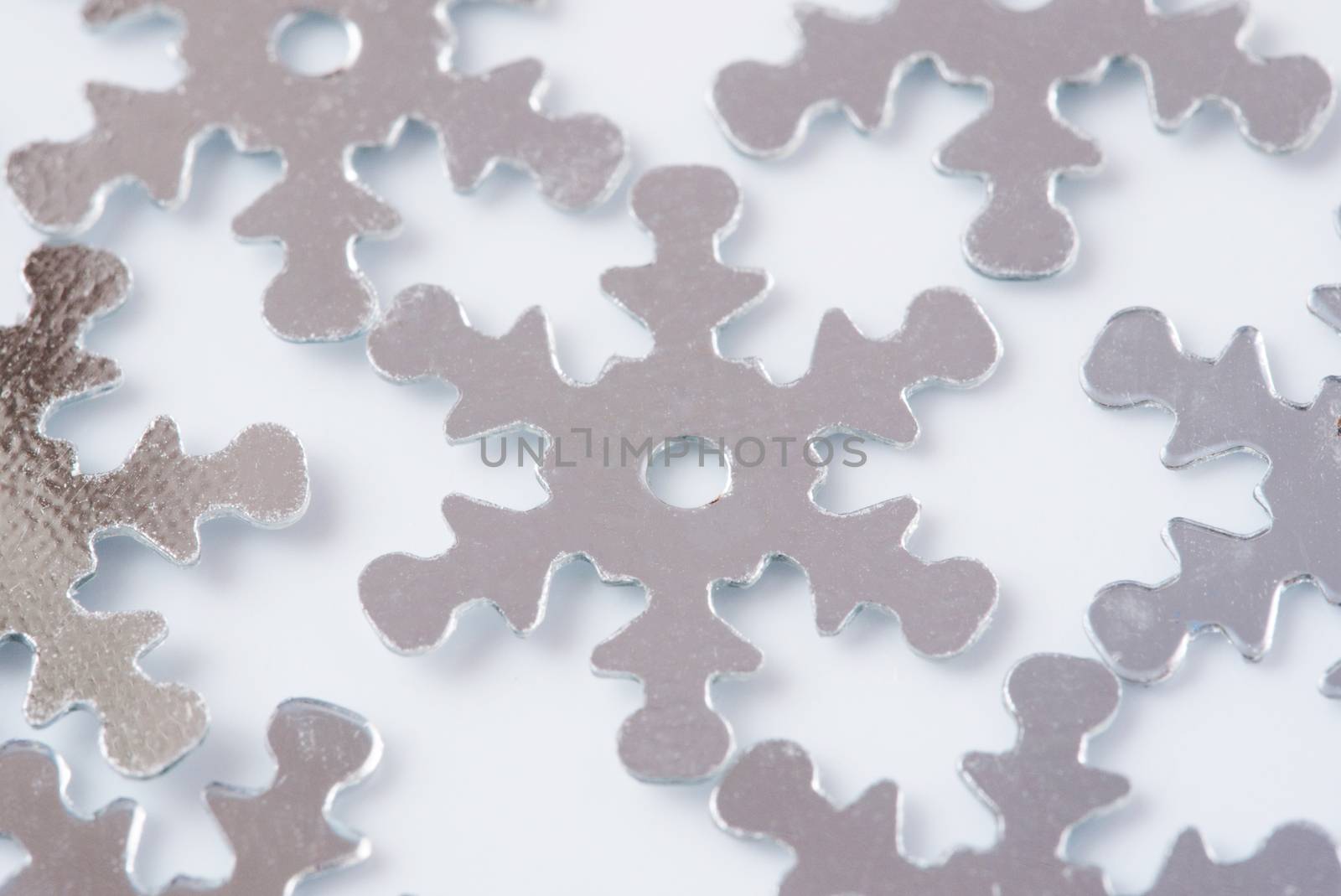 Christmas decoration of silver confetti snow flake against white background with nice boke. Close up confetti with shallow DOF