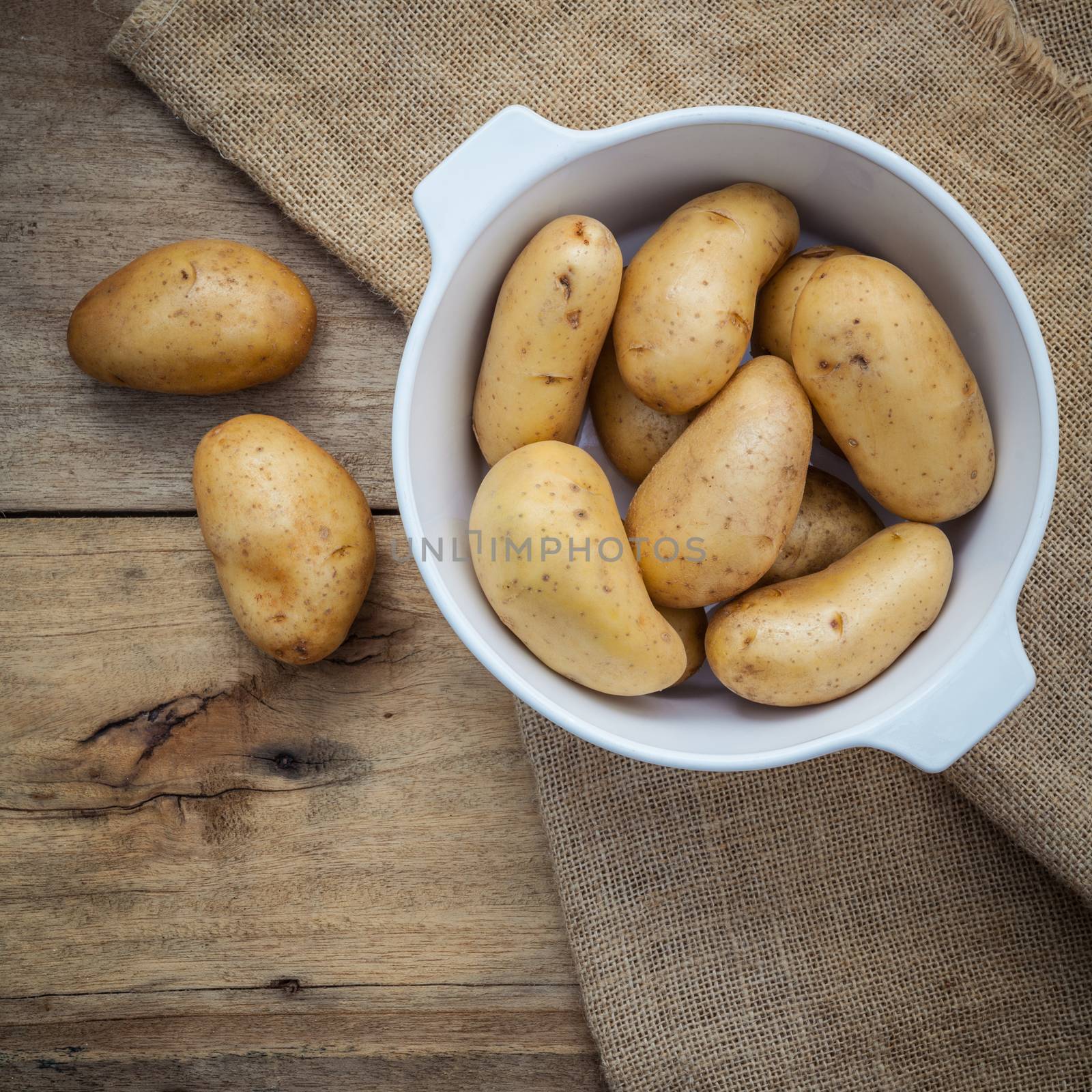 Composition of fresh organic potatoes in white ceramic bowl on h by kerdkanno