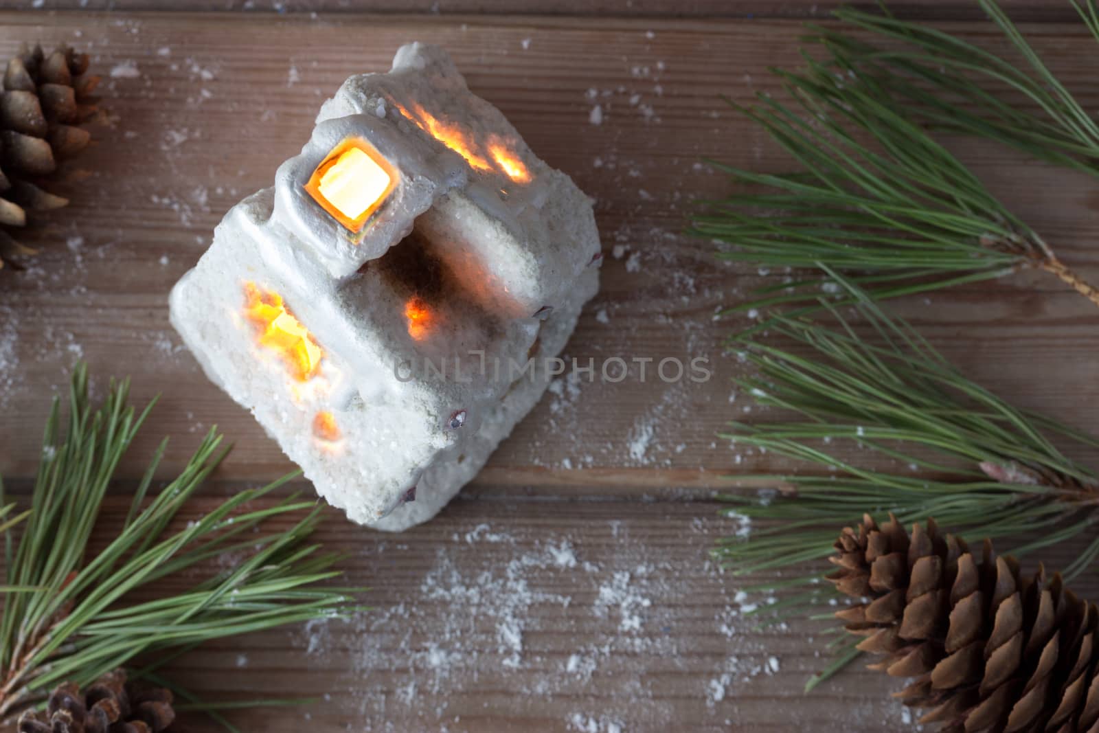 winter house candle and Christmas tree branches on wooden table