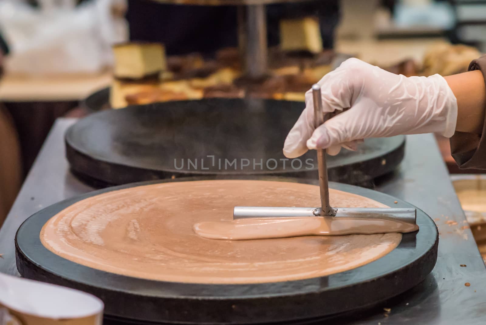 hand prepares chocolate pancake outdoors by okskukuruza
